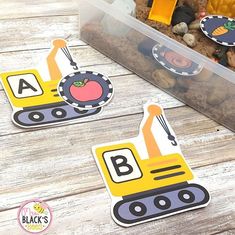 two children's construction themed magnets in a plastic container on a wooden table