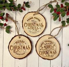 three wooden christmas ornaments hanging on a white wood background with berries and greenery around them