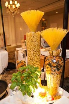 two vases filled with yellow flowers sitting on top of a white tablecloth covered table