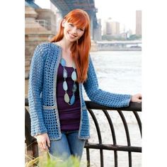 a woman with red hair is leaning on a fence near the water and smiling at the camera