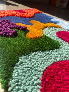 a multicolored crocheted rug on the floor with flowers all over it