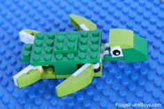 a lego turtle is made out of green and white plastic bricks, with an eye on it's shell