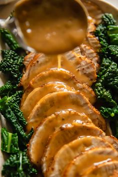 a white plate topped with meat covered in gravy next to broccoli