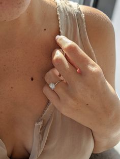 a woman with her hand on her chest wearing a diamond ring and holding onto the shoulder of her dress