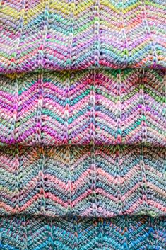 colorful knitted blankets stacked on top of each other