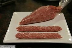 three sausages on a plate being prepared to be cooked