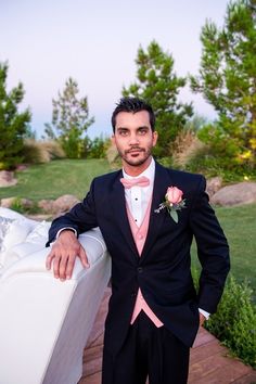 a man in a tuxedo standing on a deck next to a white couch