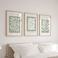 two framed pictures hang on the wall above a bed with white linens and pillows