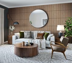 a living room filled with furniture and a large round mirror on the wall above it