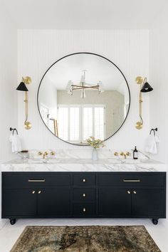 a bathroom vanity with two sinks and a large round mirror above it, along with a rug on the floor