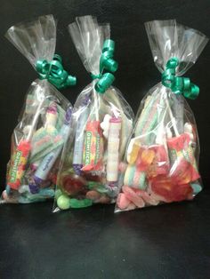 three bags filled with assorted candy on top of a black table next to each other