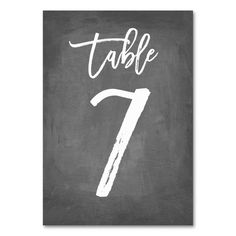 a chalkboard table number seven with the word table written in white ink on it