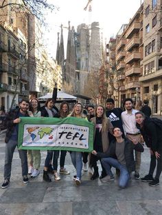 a group of people standing around each other holding a green and white banner in the middle of a city