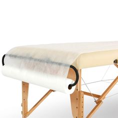 an upholstered wooden massage table with white fabric on the top and black handles