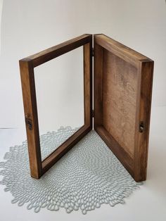 an open wooden box on top of a doily with a mirror in the middle