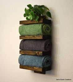 a wooden shelf with towels hanging on it and a plant growing out of the top