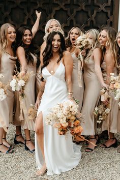 a group of women standing next to each other wearing dresses and holding bouquets in their hands