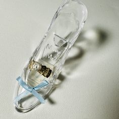 an empty glass bottle with a blue ribbon tied around it on top of a white surface