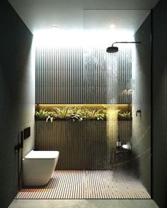 a bathroom with a toilet, shower and plants on the wall in front of it