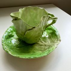 a green leafy bowl sitting on top of a saucer