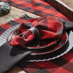 a red and black plaid table cloth with napkins on it is sitting on a plate