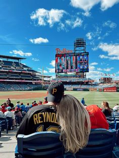 two people are sitting in the stands at a baseball game, looking out into the field