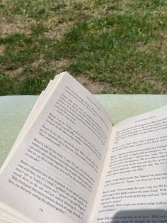 an open book sitting on top of a table next to a green grass covered field