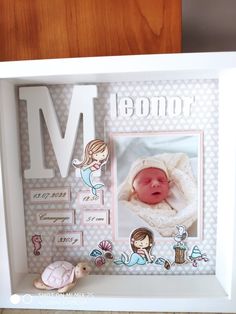 a baby's photo in a white frame with the letter m on it and other items