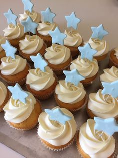 cupcakes with white frosting and blue stars on top are sitting on a tray