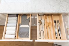 an open drawer with utensils and spoons in it