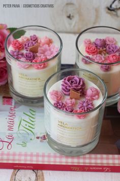 three candles with flowers in them sitting on a table