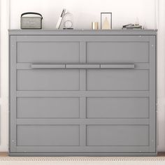 a gray dresser sitting in the corner of a room next to a clock and other items