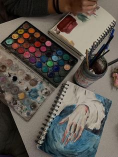 a person is painting with watercolors on a table next to other art supplies