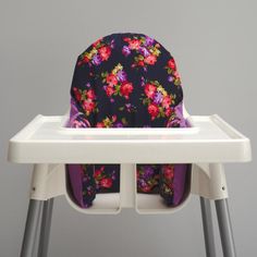 a high chair with a purple flowered seat cover on the top and bottom part