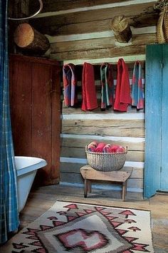 an old fashioned bathroom with wooden walls and wood flooring, including a rug on the floor