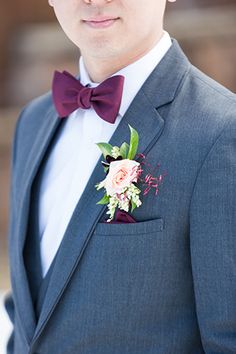 a man in a suit and bow tie is wearing a boutonniere with flowers on it