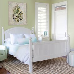 a white bed sitting in a bedroom next to a chair and painting on the wall