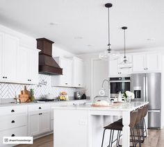 a kitchen with white cabinets and an island that has stools at the counter top