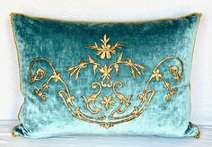 a blue velvet pillow with gold embroidered designs on it