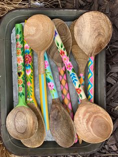 several wooden spoons are lined up in a tray with different designs and colors on them