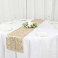 the table is set with white and gold linens