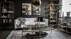 a living room with black walls and gold accents on the coffee table in front of the couch