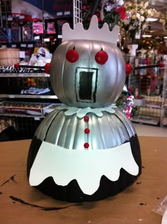 a metal pumpkin with a crown on it's head sitting on top of a table