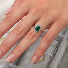 a woman's hand with an emerald and diamond ring