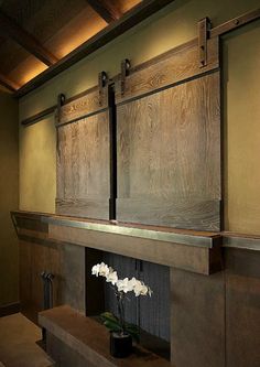 a vase with white flowers sitting on top of a wooden shelf next to a fire place