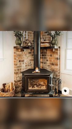 a wood burning stove in front of a brick wall with potted plants on top