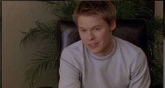 a young man sitting in a chair holding a remote