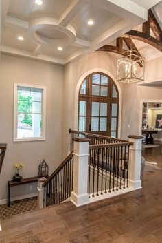 a large open floor plan with wood floors and white walls, an arched window on the far wall