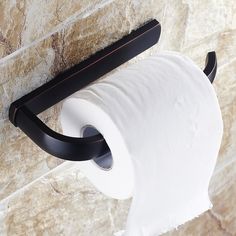 a roll of toilet paper is hanging on the wall next to a black metal holder