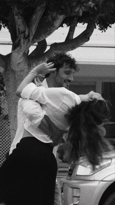 a man and woman dancing in front of a tree